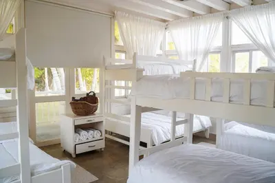 a bedroom with white bunk beds and a window at Quinta del Mar Tintipán in Isla Mucura