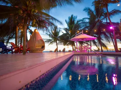 a resort swimming pool with a pink umbrella and palm trees at Quinta del Mar El Paraiso in Tolú