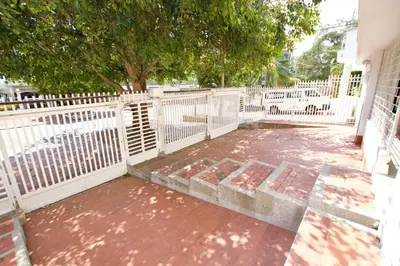 a patio with a white fence and a tree at QuillaHost Guesthouse in Barranquilla