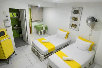 a room with two beds and a fan at QuillaHost Guesthouse in Barranquilla