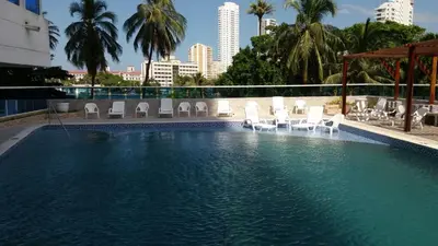 a large swimming pool with white chairs and a city skyline at Apartamento Boutique Cartagena in Cartagena de Indias