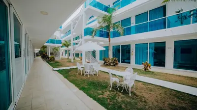 a patio with white tables and chairs in front of a building at Palma Linda Coveñas by Bernalo Hotels in Coveñas