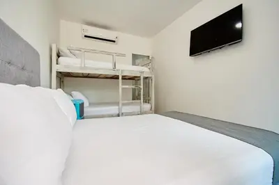 a bedroom with a bed and a tv and bunk beds at Palma Linda Coveñas by Bernalo Hotels in Coveñas