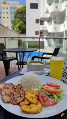 a plate of food with rice and tomatoes on a table at Hotel Dorado BAQ in Barranquilla