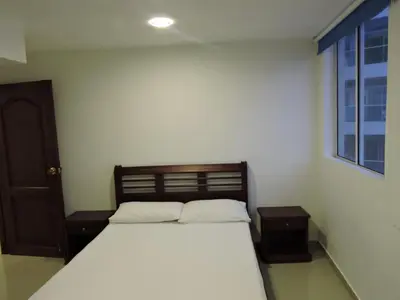 a bedroom with a bed with white sheets and a window at Apartamento Laguito Bocagrande in Cartagena de Indias