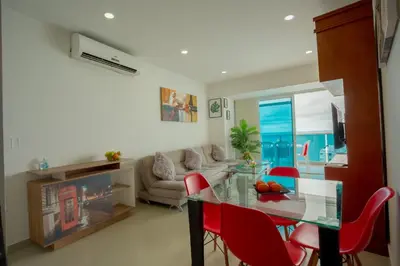 a living room with a glass table and red chairs at Apartamento Vista Mar 1707 in Cartagena de Indias