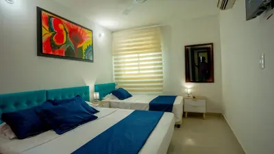 a bedroom with two beds and a painting on the wall at Apartamento Vista Mar 1707 in Cartagena de Indias
