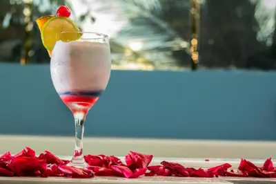 a drink sitting on a table with red rose petals at Voilá Signature Casa Isabel in Cartagena de Indias