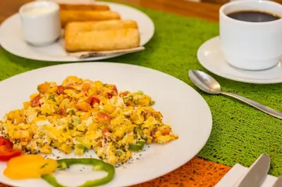 a plate of eggs and vegetables on a table with a cup of coffee at Voilá Signature Casa Isabel in Cartagena de Indias