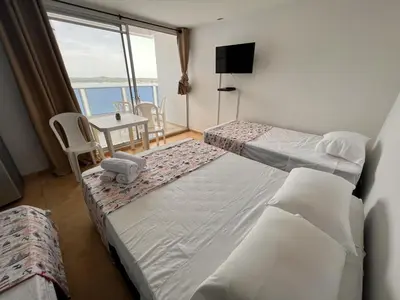 a room with two beds and a table and a window at Apartamento Nuevo Conquistador in Cartagena de Indias