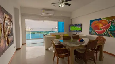 a dining room with a table and chairs and a television at Poseidon Lake Apartments in Cartagena de Indias