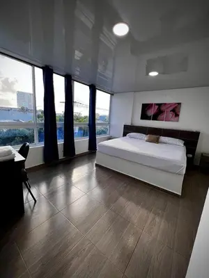 a large bedroom with a bed and large windows at Hotel Sofichic Barranquilla in Barranquilla