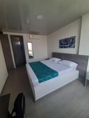 a bedroom with a large white bed with a green blanket at Hotel Sofichic Barranquilla in Barranquilla
