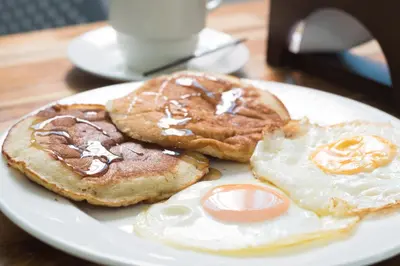 two pancakes and an egg on a plate on a table at Hotel Aquarius in Barranquilla
