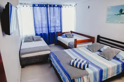 two beds in a room with blue curtains at Apartamento piso 12 y 17 Welch in Cartagena de Indias