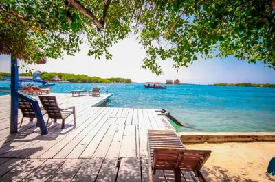 a dock with chairs and a boat in the water at Isla Los Erizos EcoHouse in Isla Grande