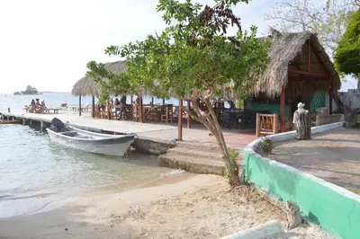 a boat is docked next to a restaurant on the water at Isla Los Erizos EcoHouse in Isla Grande