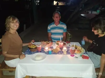 a man and two women sitting around a table with a cake at Isla Los Erizos EcoHouse in Isla Grande