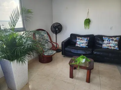 a living room with a black leather couch and plants at Cartagena El Laguito Apto cerca a la playa in Cartagena de Indias