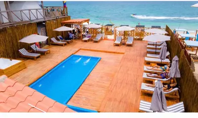 a swimming pool on a beach with chairs and umbrellas at La Cabaña Glamping Geronimo in Playa Blanca