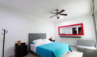a bedroom with a bed and a ceiling fan and a mirror at Apartasuite Morros Vitri in Cartagena de Indias