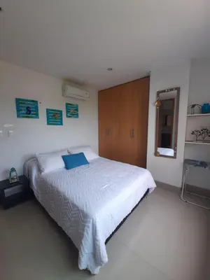 a bedroom with a white bed and a wooden cabinet at Bello Horizonte * Unido Al Mar in Santa Marta
