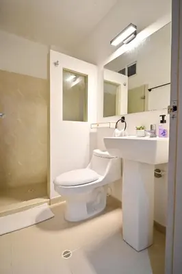 a white bathroom with a toilet and a sink at Hotel SEREMA in Cartagena de Indias
