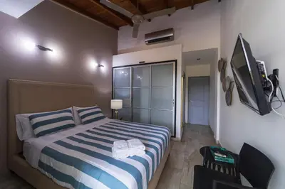 a bedroom with a blue and white striped bed and a tv at Hotel SEREMA in Cartagena de Indias