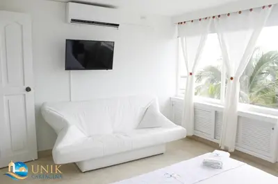 a white couch in a white room with a window at Apartamento Unik Cartagena Edificio Faro Tequendama in Cartagena de Indias