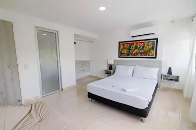 a white bedroom with a bed and a painting on the wall at Apartamento Unik Cartagena Edificio Faro Tequendama in Cartagena de Indias