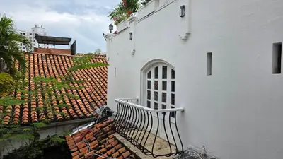 a white building with a gate next to a roof at Hotel Casa la Tablada in Cartagena de Indias