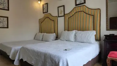 a bedroom with two beds with white sheets at Hotel Casa la Tablada in Cartagena de Indias