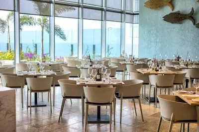 a restaurant with tables and chairs and windows at Estelar Cartagena de Indias Hotel y Centro de Convenciones in Cartagena de Indias