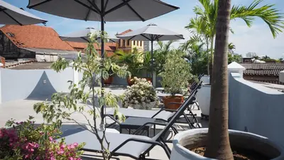 a patio with chairs and an umbrella and plants at Hotel Casa Cytia in Cartagena de Indias