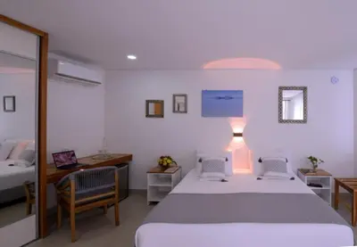 a bedroom with a bed and two chairs and a desk at Hotel Casa Cytia in Cartagena de Indias