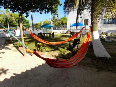 a hammock hanging from two palm trees on a beach at Ortimar in Tolú