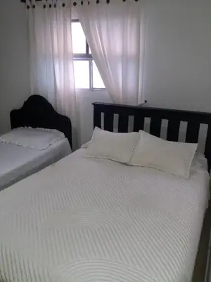 a bedroom with two beds with white sheets and a window at Edificio Torre Centauro in Cartagena de Indias