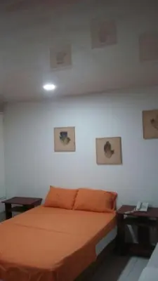 a bedroom with an orange bed and two tables at Edificio Nuevo Conquistador in Cartagena de Indias