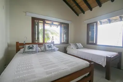 two beds in a room with two windows at Cabana SalSiPuedes in Tintipan Island