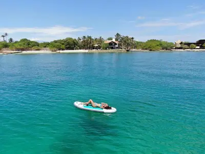 a person laying on a paddle board in the water at Cabana SalSiPuedes in Tintipan Island