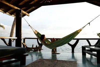 a woman sitting in a hammock overlooking the ocean at Cabana SalSiPuedes in Tintipan Island