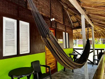 a hammock in a restaurant with tables and chairs at Eco Hotel Bosque Encantado in Isla Grande