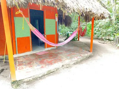 an orange and green building with a hammock in it at Eco Hotel Las Palmeras in Isla Grande