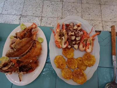 two plates of food with crabs and potatoes on a table at ECOHOTEL LAS FLORES Econativo in Isla Grande
