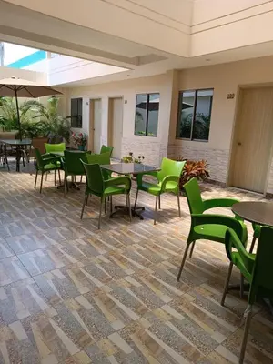 a patio with green chairs and tables in a building at Hotel Prado 53 in Barranquilla