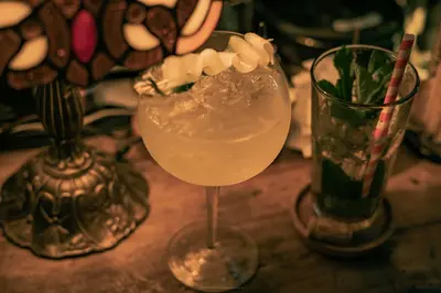 a drink in a glass sitting on a table with two glasses at Casa Be Getsemaní in Cartagena de Indias