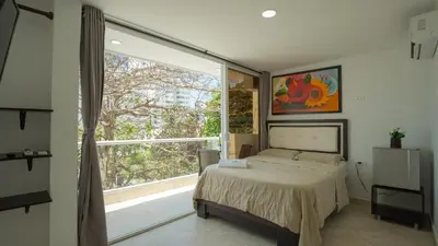 a bedroom with a bed and a large window at Hollywood Beach Suite in Cartagena de Indias