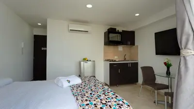 a bedroom with a bed and a kitchen with a table at Hollywood Beach Suite in Cartagena de Indias