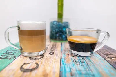 a cup of coffee and a glass of coffee on a wooden table at Hotel Masinda in Cartagena de Indias