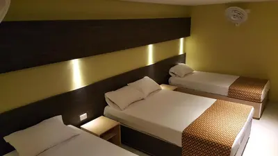 a small room with two beds and a couch at Hotel 56 Avenue Plaza in Barranquilla